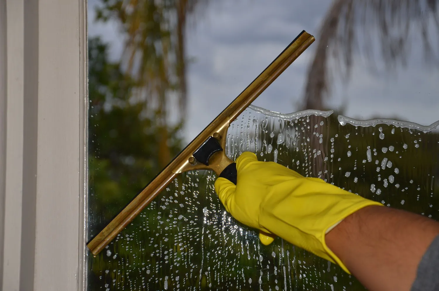 A squeegee clearing water from a window pane